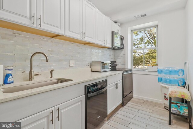 kitchen with appliances with stainless steel finishes, tasteful backsplash, light hardwood / wood-style floors, sink, and white cabinets