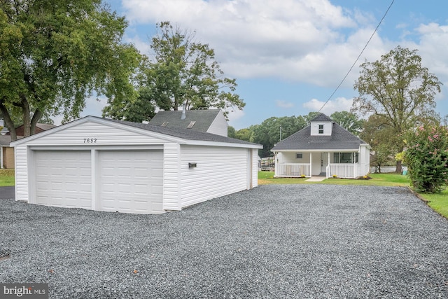 garage featuring covered porch and a lawn