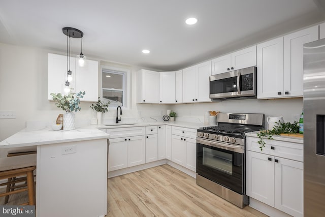 kitchen with a kitchen bar, appliances with stainless steel finishes, kitchen peninsula, and white cabinetry