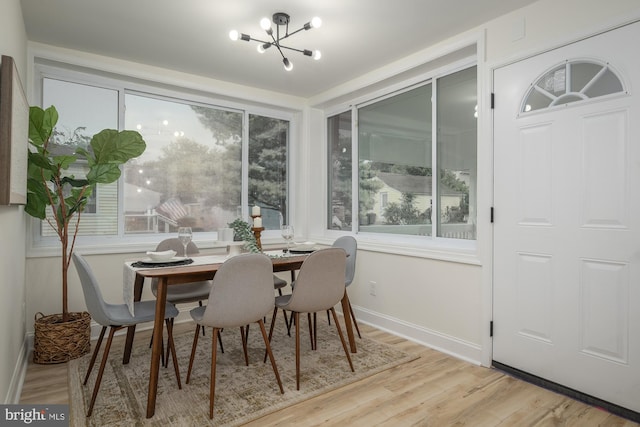 dining room with a notable chandelier, a healthy amount of sunlight, and light wood-type flooring