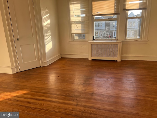 unfurnished room featuring dark hardwood / wood-style flooring and radiator heating unit