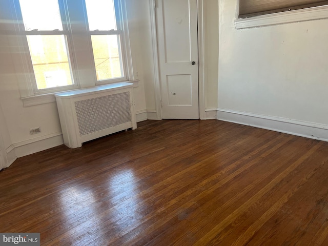 spare room featuring radiator and dark hardwood / wood-style floors