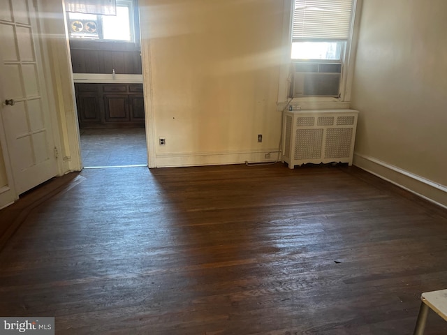 empty room featuring radiator and dark hardwood / wood-style floors