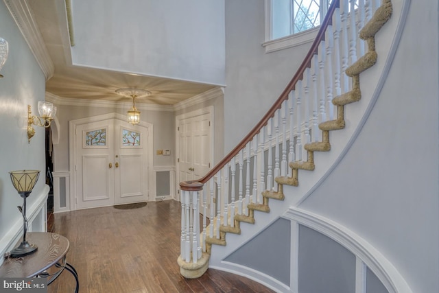 entryway featuring a towering ceiling, ornamental molding, and hardwood / wood-style flooring