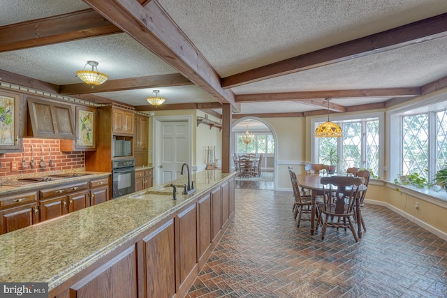 kitchen featuring custom exhaust hood, a textured ceiling, gas stovetop, sink, and black oven