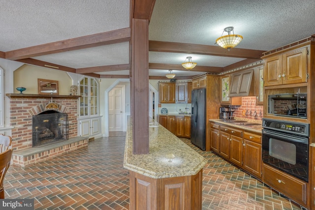 kitchen featuring a textured ceiling, light stone countertops, black appliances, tasteful backsplash, and a brick fireplace