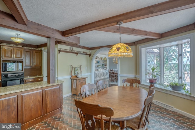 dining space featuring a textured ceiling and beam ceiling