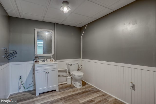 bathroom featuring vanity, toilet, hardwood / wood-style floors, and a drop ceiling