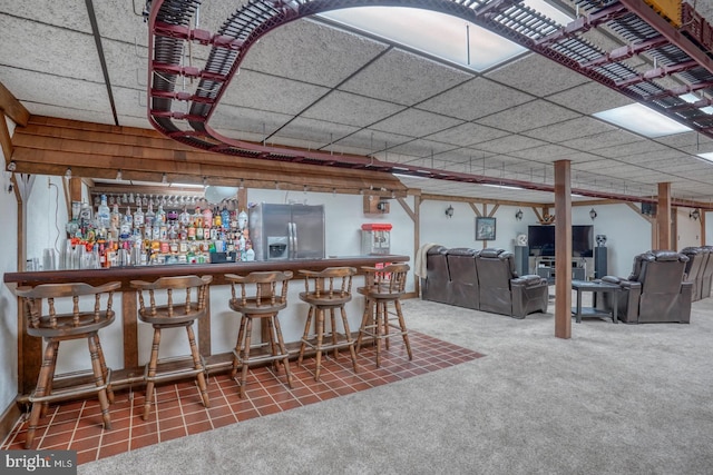 bar featuring stainless steel refrigerator with ice dispenser, a paneled ceiling, and carpet