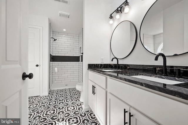 bathroom featuring vanity, tiled shower, toilet, and tile patterned floors