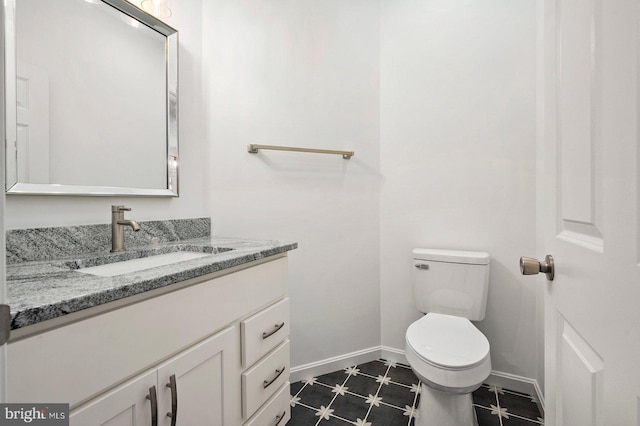 bathroom with baseboards, toilet, and vanity