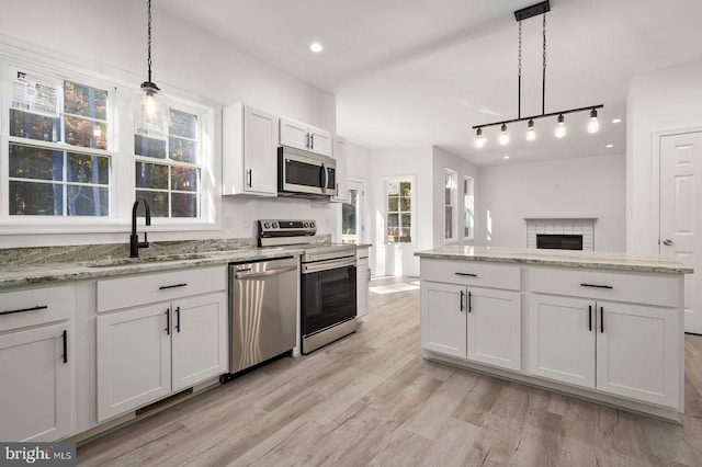 kitchen featuring white cabinetry, decorative light fixtures, stainless steel appliances, and light wood-type flooring