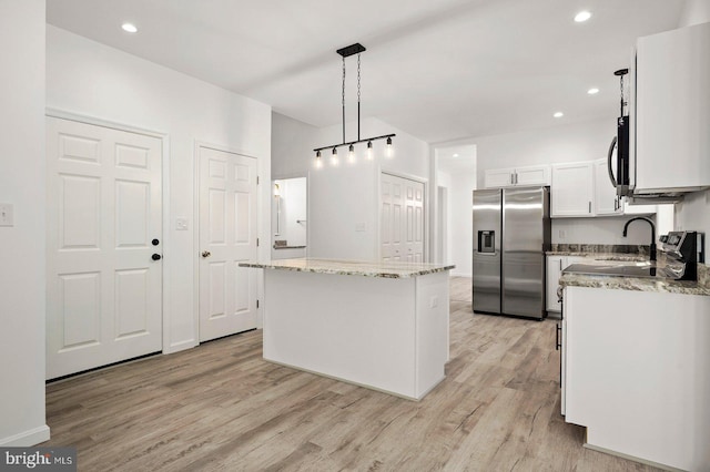 kitchen with light stone countertops, stainless steel fridge with ice dispenser, white cabinets, light wood-type flooring, and a center island