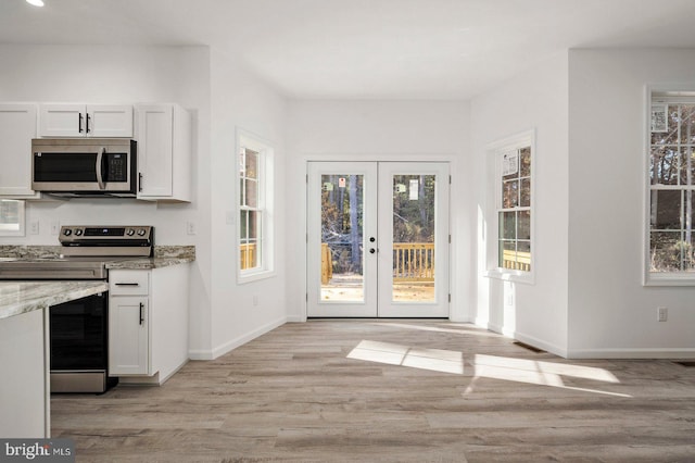 interior space with light wood-style flooring, french doors, and baseboards