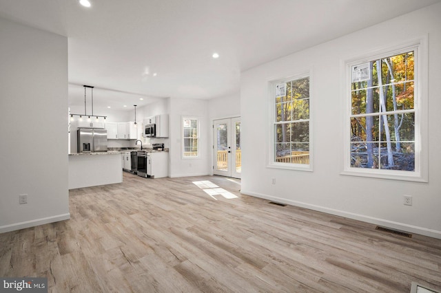 unfurnished living room with recessed lighting, plenty of natural light, visible vents, and light wood-type flooring