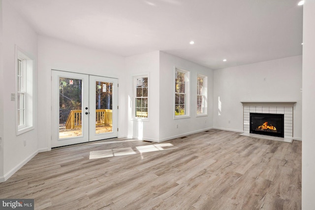 unfurnished living room with french doors, light wood-type flooring, and baseboards