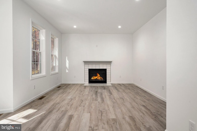 unfurnished living room with visible vents, baseboards, a tiled fireplace, recessed lighting, and light wood-style floors