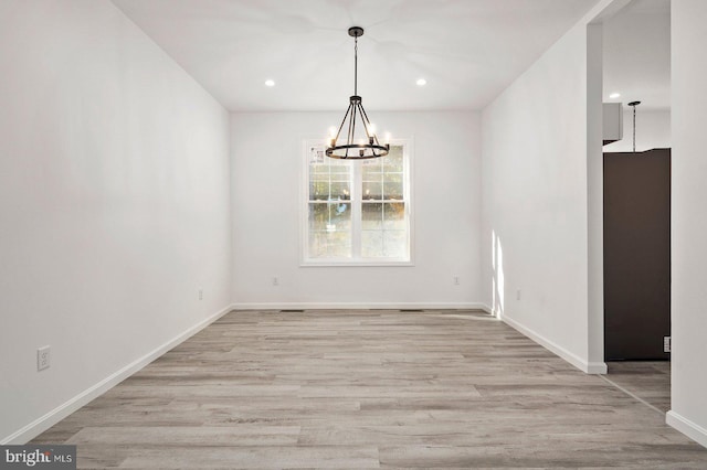 unfurnished dining area with recessed lighting, baseboards, an inviting chandelier, and wood finished floors