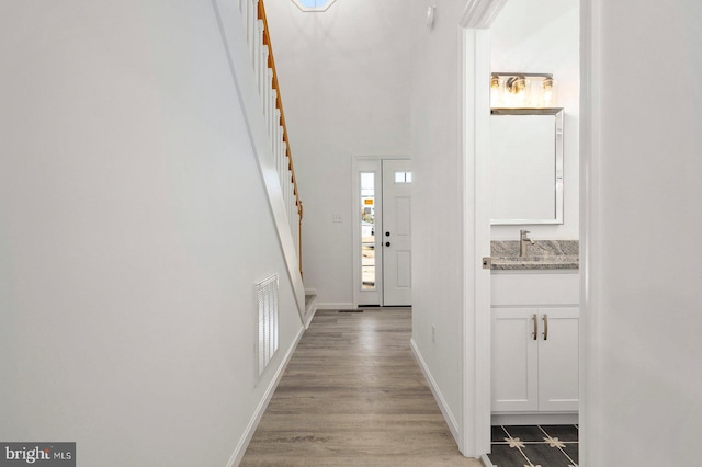 foyer with stairs, light wood-style floors, visible vents, and baseboards