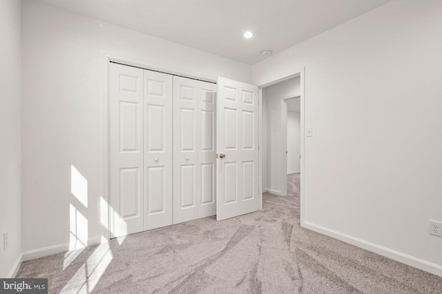 unfurnished bedroom featuring light colored carpet and a closet