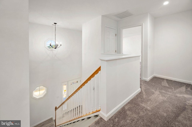 stairs with carpet floors and a chandelier