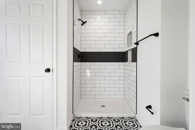 bathroom featuring tiled shower, toilet, and tile patterned flooring