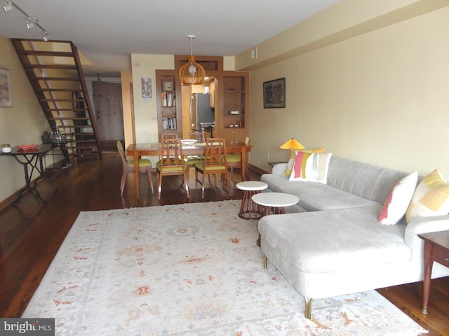 living area featuring rail lighting, stairs, and wood finished floors