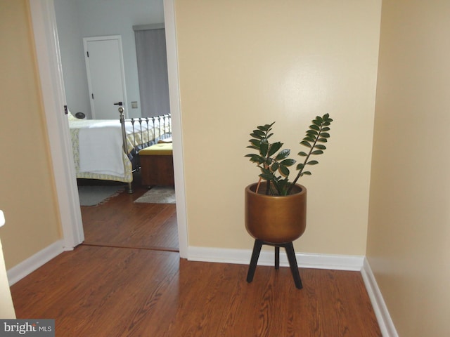 hallway featuring wood finished floors and baseboards