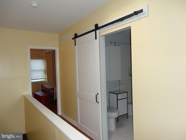 corridor featuring a barn door and tile patterned floors