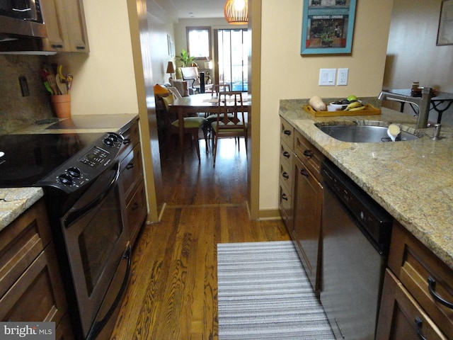 kitchen featuring stainless steel appliances, a sink, light stone counters, and dark wood-style floors