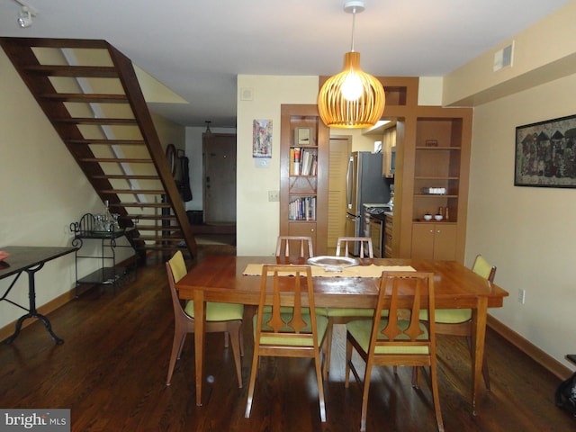 dining space with visible vents, stairway, baseboards, and wood finished floors