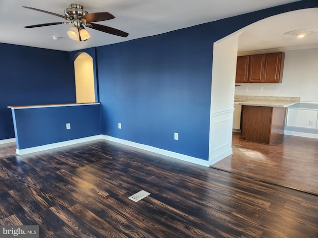 unfurnished room featuring dark wood finished floors, visible vents, arched walkways, and baseboards