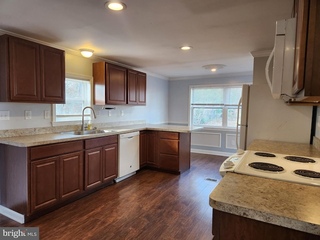 kitchen with white appliances, a peninsula, dark wood-style flooring, a sink, and light countertops