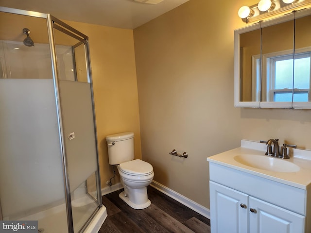 full bath with toilet, a stall shower, wood finished floors, baseboards, and vanity