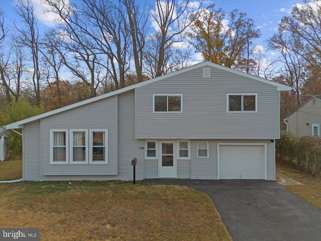 split level home featuring aphalt driveway, an attached garage, and a front yard