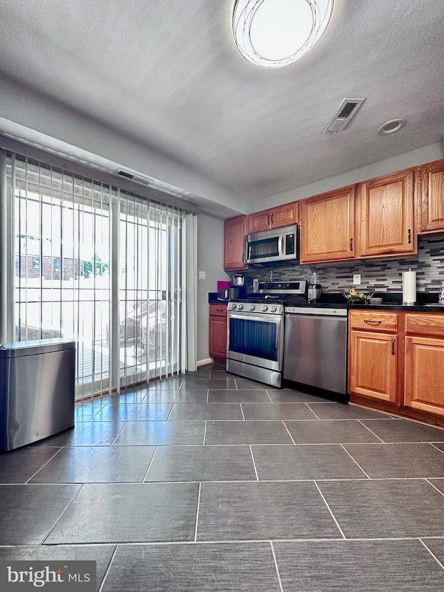 kitchen with appliances with stainless steel finishes, tasteful backsplash, and a textured ceiling