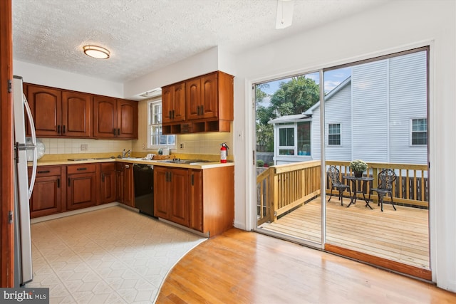 kitchen featuring backsplash, appliances with stainless steel finishes, light hardwood / wood-style flooring, and a textured ceiling