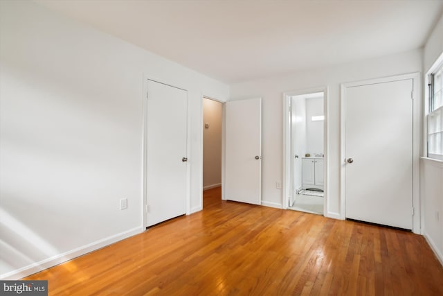 unfurnished bedroom featuring hardwood / wood-style floors and ensuite bathroom