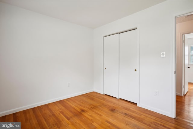 unfurnished bedroom featuring wood-type flooring and a closet