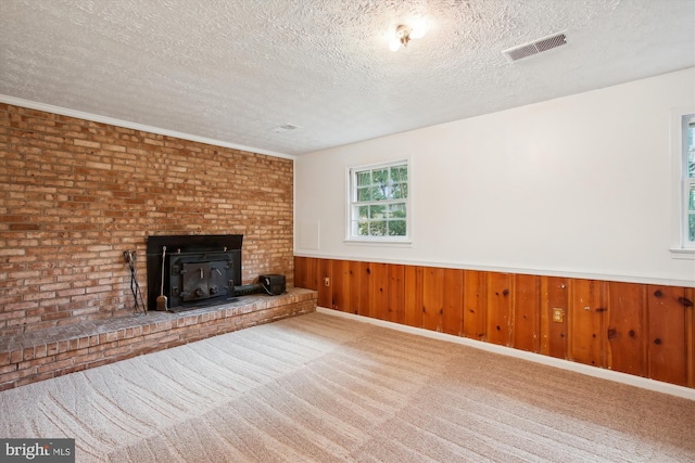 unfurnished living room with wood walls, carpet, and a textured ceiling