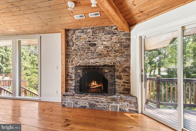 unfurnished living room featuring plenty of natural light, a stone fireplace, wood-type flooring, and wooden ceiling