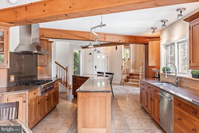 kitchen featuring a center island, a healthy amount of sunlight, appliances with stainless steel finishes, and wall chimney range hood