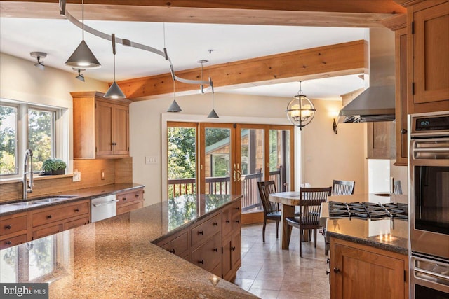 kitchen featuring ventilation hood, dark stone countertops, sink, pendant lighting, and stainless steel dishwasher