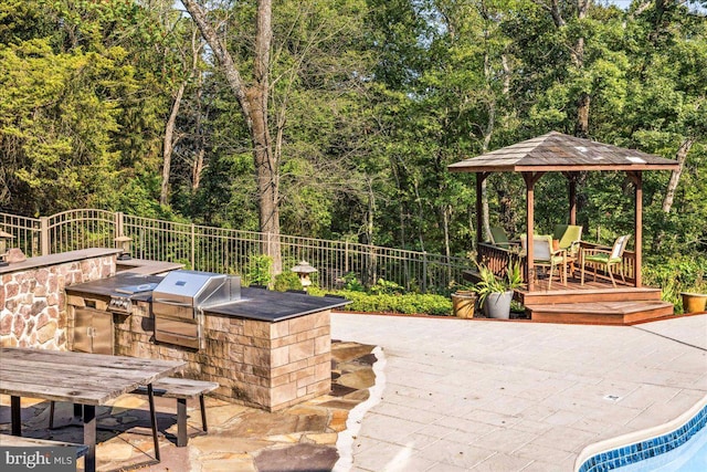 wooden terrace featuring a patio area, an outdoor kitchen, and a grill