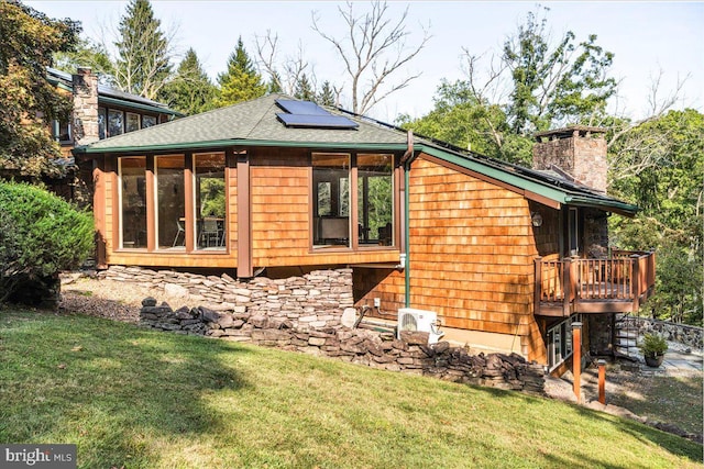 view of side of home with a yard, solar panels, and a wooden deck