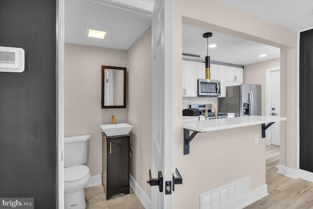 bathroom with visible vents, toilet, a sink, tasteful backsplash, and baseboards