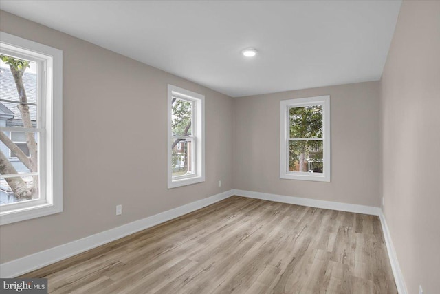 empty room with plenty of natural light, baseboards, and light wood-type flooring