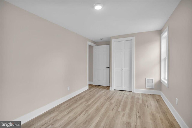 unfurnished bedroom featuring visible vents, baseboards, a closet, and light wood-style flooring