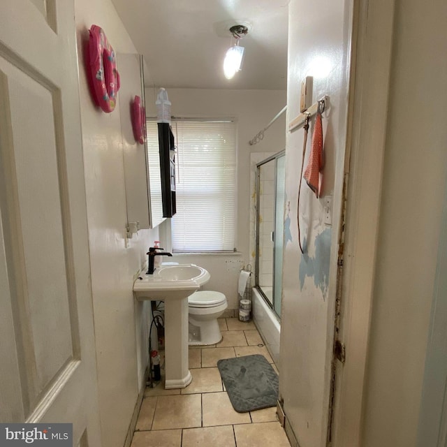 full bathroom featuring combined bath / shower with glass door, toilet, sink, and tile patterned floors