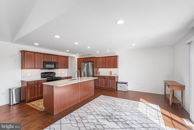 kitchen with sink, black appliances, dark hardwood / wood-style floors, a kitchen bar, and a kitchen island with sink